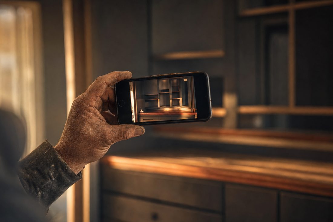 A phone held up photographing finished work on a job site in warm afternoon light